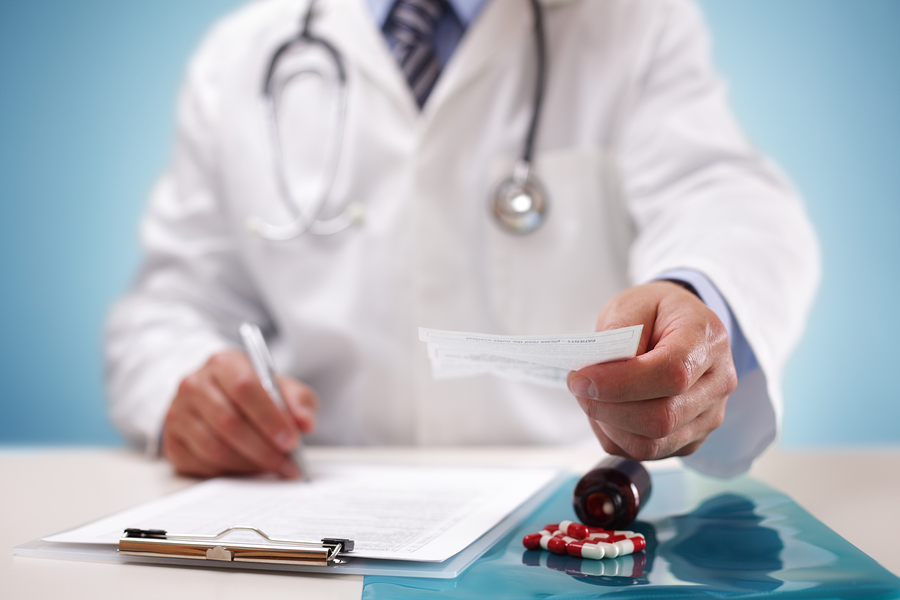 Doctor writing and holding a patient prescription after medical